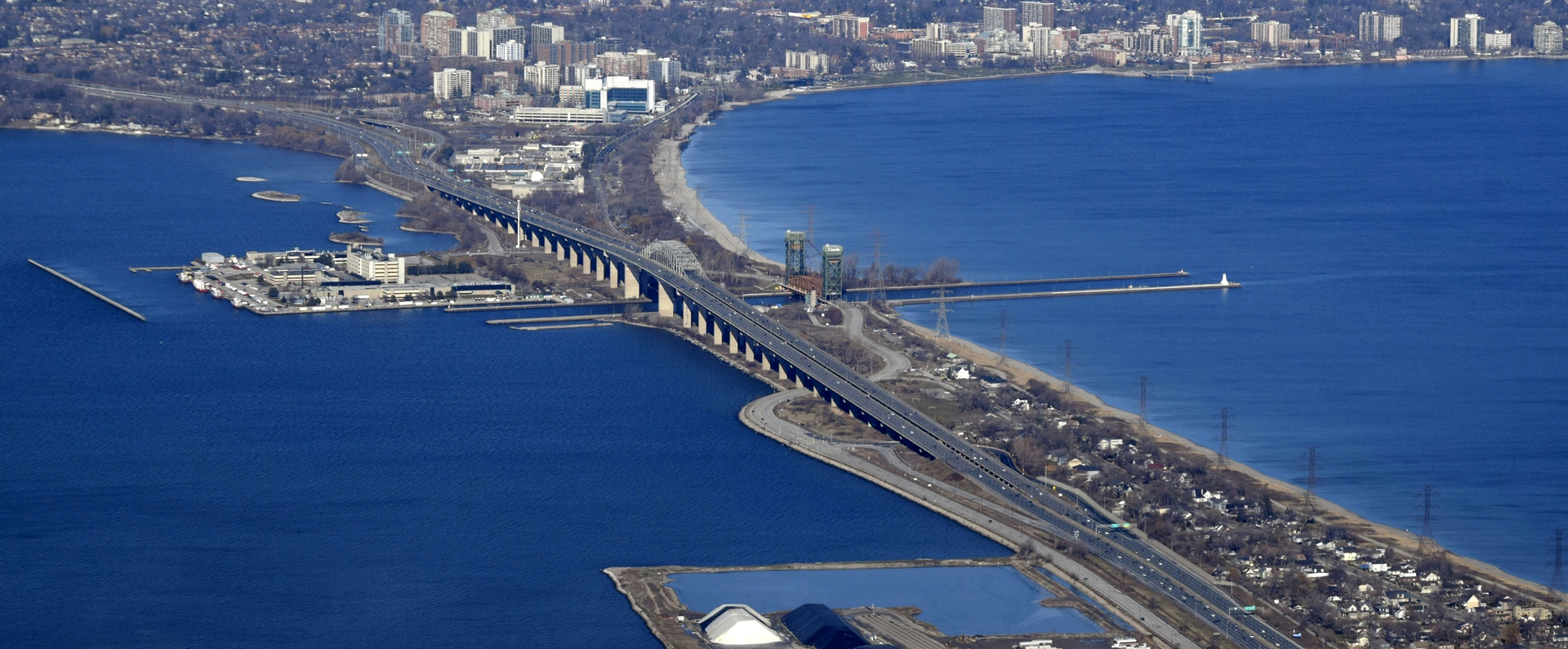 aerial-view-of-the-Skyway-bridge-in-Hamilton-Ontario-Canada Aerial view of the Skyway Bridge in Hamilton, Ontario, Canada, spanning a large body of water with urban development visible on both sides.